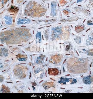 Seamless texture of asymmetric masonry made of multicolored stones. Top view. Stock Photo