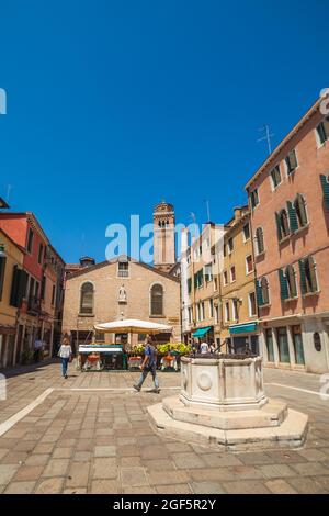 VENICE, ITALY - JUNE 15, 2016 a typical Venetian square called campo San Toma, an ancient well for collecting water and Sculeta dei calegheri in the background Stock Photo