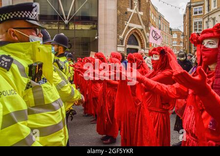 London, UK. 23rd Aug, 2021. Red Rebel Brigade demonstrators gesture in front of police officers during the protest in Covent Garden. Extinction Rebellion protesters gathered in central London for the start of their two-week campaign entitled Impossible Rebellion, calling on the UK Government to act meaningfully on the ecological and climate crisis. Credit: SOPA Images Limited/Alamy Live News
