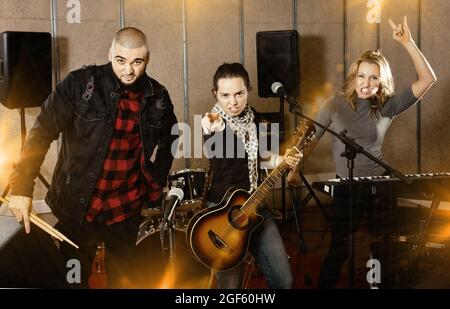 Three bandmates posing together with musical instruments in rehe Stock Photo