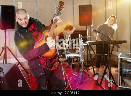 Bearded guy soloist playing guitar in studio Stock Photo