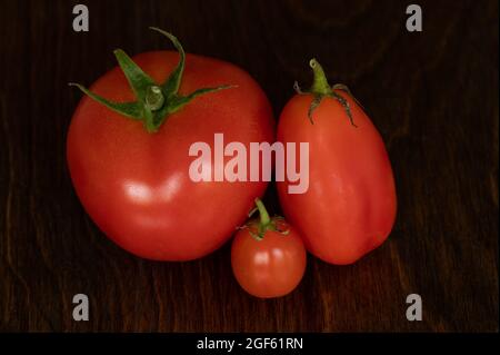 Top View of Three Tomatoes of Different Sizes on Wood Background Stock Photo