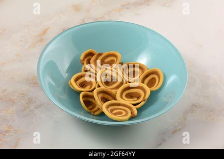 Black sesame and cinnamon umbrella cookies in blue snack bowl on table Stock Photo