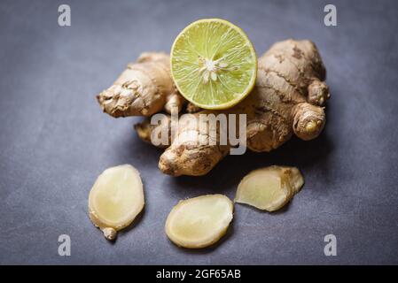 Fresh ginger root on dark background with sliced ginger and lemon lime Stock Photo
