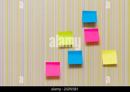 Many blank colorful memory stickers on striped multicolored background. Blank space on multi-colored office stickers. Busy day, business concept. Stock Photo