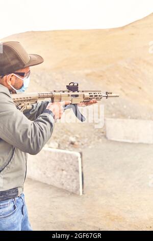 Men practicing shooting with a assault rifle at target. Selective Focus Stock Photo