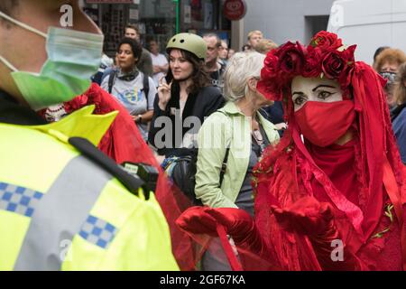 London, UK. 23rd August, 2021. Members of the Extinction Rebellion Red Rebel Brigade line up in front of Metropolitan Police officers during the first day of Impossible Rebellion protests in the Covent Garden area. Extinction Rebellion are calling on the UK government to cease all new fossil fuel investment with immediate effect. Credit: Mark Kerrison/Alamy Live News Stock Photo