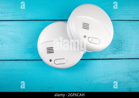 Two smoke detectors on a blue painted wooden surface. Stock Photo