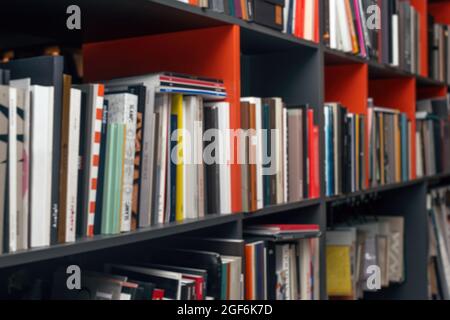 Blurred background with multi-colored books and catalogs on the shelves. Stock Photo