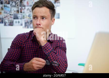 Portrait of desperate graphic designer taking off glasses and looking away after sending wrong design layout to client Stock Photo