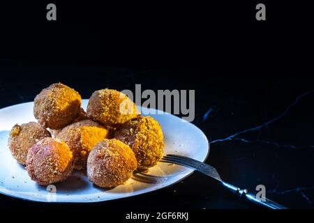 Premium Photo  Cheese balls with garlic and dill inside for a snack in a  plate on a black background.