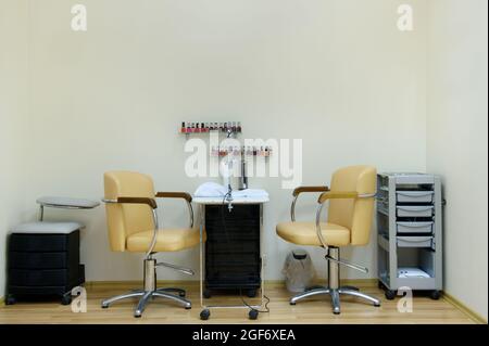 place for a manicure in a beauty salon in bright colors.Two chairs and a table in the nail care room. Stock Photo