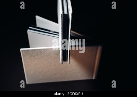 Composition of photo books in natural white leather of different sizes. The white paper on a dark background. Stock Photo
