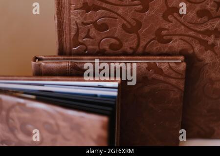 Composition of photo books in natural brown leather of different sizes. Fragment of a photobook binding Stock Photo
