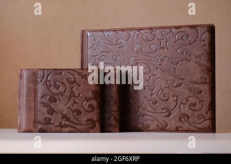 Composition of photo books in natural brown leather of different sizes. Fragment of a photobook binding Stock Photo