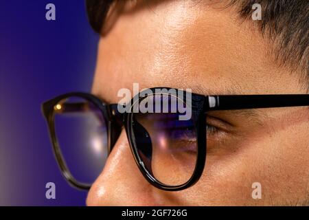 Serios young hacker looking at pc, computer, laptop screen wearing protective eyeglasses Stock Photo