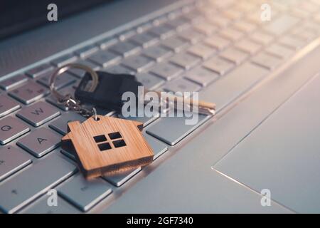 Mortgage concept with keys and house-shaped key ring on laptop keyboard. Find dream house in internet concept. Online assistance in searching dwelling Stock Photo