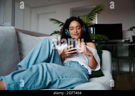 Mixed race female teen relaxing at home texting on cellular device Stock Photo