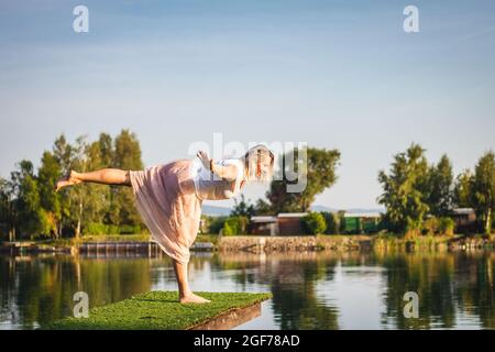 Beautiful plus size woman doing yoga and relaxation exercise in nature at summer day. Outdoor healthy activity. Body positive Stock Photo