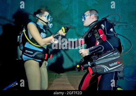 Young woman dives in indoor diving centre Monte Mare and does diving exercises with diving instructor during diving course, Rheinbach, North Stock Photo