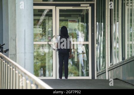 Darmstadt, Germany. 24th Aug, 2021. A man stands at the entrance to building L201 on the Lichtwiese campus of the TU Darmstadt. The day before, six people had been brought to clinics here with symptoms of poisoning, a 30-year-old student was in critical condition. The suspected poison attack is now being investigated for attempted murder. Credit: Frank Rumpenhorst/dpa/Alamy Live News Stock Photo