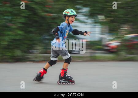 Ukraine, Kyiv - 20 June 2021: Boy training for inline skates. Rollerblade Inline Skates, Author Helmet, Powerslide Protection . Editorial Stock Photo