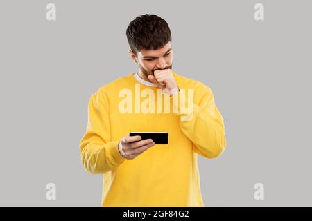 puzzled young man with smartphone Stock Photo