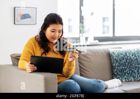 asian woman with tablet pc and credit card at home Stock Photo