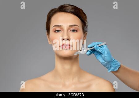 beautiful young woman and hand with scalpel Stock Photo