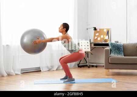 woman doing squats with fitness ball at home Stock Photo