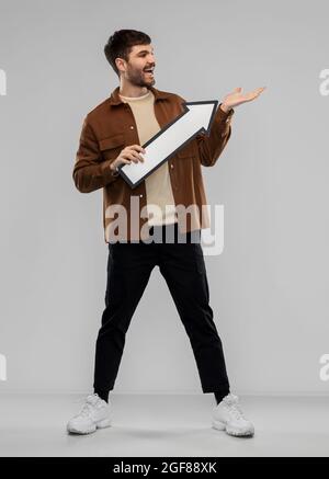 smiling young man holding big white arrow Stock Photo