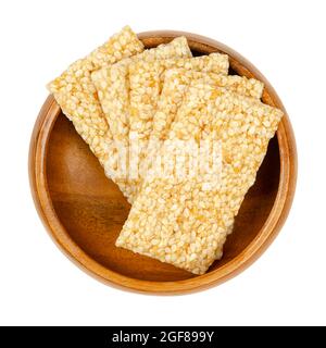 Sesame seed candy bars, in a wooden bowl. Sesame brittle or crunch, a confection of sesame seeds and honey pressed into flat bars, a popular snack. Stock Photo