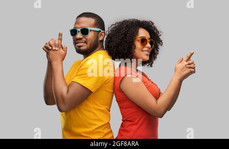 african couple in sunglasses making gun gesture Stock Photo