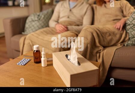 box of tissues and drugs over sick couple at home Stock Photo