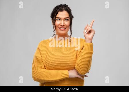 happy smiling young woman pointing finger up Stock Photo