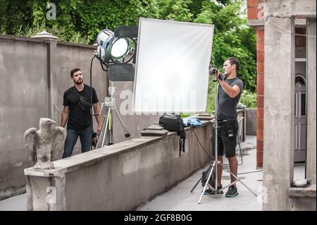 Behind the scene. Filmmaking lighting technician electric engineer adjusting and setup lights for movie film scene. Light Department. Film Crew Stock Photo