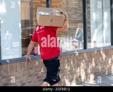 Truro, UK. 24th Aug, 2021. People make the most of the glorious sunshine in Truro, Cornwall. A DPD delivery driver walks with a parcel on his shoulder. The forecast is for 19C, sunny intervals and a moderate breeze. Credit: Keith Larby/Alamy Live News Stock Photo