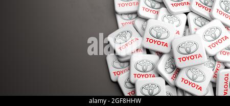 Logos of the Japanese mass car manufacturer Toyota on a heap on a table. Copy space. Web banner format. Stock Photo