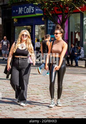 Dundee, Tayside, Scotland, UK. 24th Aug, 2021. UK weather: Glorious warm sunshine across North East Scotland with temperatures reaching 21°C. The late Summer heatwave attracts many local resident to take the day out to enjoy socialising outside after months of Coronavirus lockdowns. Two glamorous young women enjoying the weather walking together having fun in Dundee city centre. Credit: Dundee Photographics/Alamy Live News Stock Photo