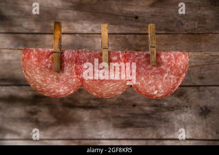 Presentation of slices of salami hanging by a thread Stock Photo