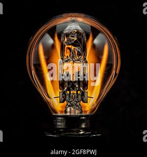 Edison style light bulb with a gold light in the darkness Stock Photo