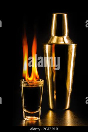 glass of flaming alcoholic drink, vodka or liquor on fire, black background Stock Photo
