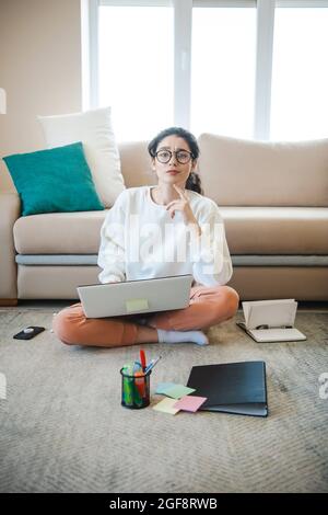 Woman solving problem on the floor during homework. Educational concept photo with hard-working student. Exam preparation Stock Photo
