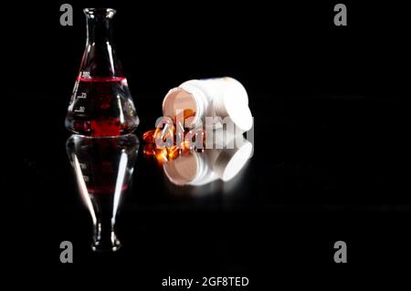Transparent yellow Pills spilling out of pill bottle on black background with reflection from the surface. Medicinal chemistry conical and drug develo Stock Photo