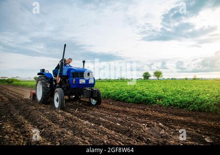 A farmer is cultivating a farm field. Seasonal worker. Recruiting workers with driving skills of agricultural machinery. Land cultivation. Farming. Sm Stock Photo