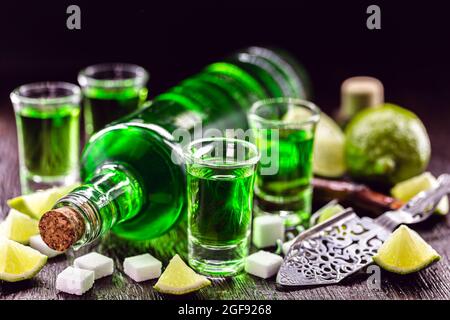 doses of absinthe with brown sugar cubes. distillate of absinthe in a glass and lemon, stainless steel spoon isolated on black background Stock Photo