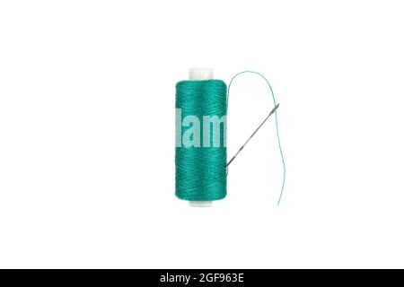 The needle is stuck in a spool of green thread. The thread passes through the eye of the needle. Copy space. Stock Photo