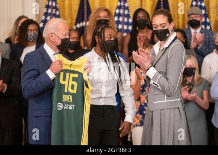 United States President Joe Biden is given a team jersey Jewell Loyd, center and Breanna Stewart, right, of the Seattle Storm after they won the 2020 WNBA Championship at the White House in Washington, DC on Monday, August 23, 2021. Credit: Ken Cedeno / Pool via CNP Stock Photo