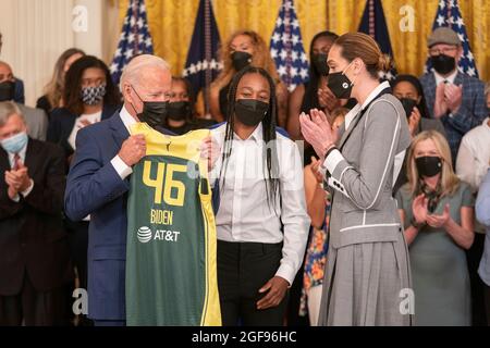 United States President Joe Biden is given a team jersey Jewell Loyd, center and Breanna Stewart, right, of the Seattle Storm after they won the 2020 WNBA Championship at the White House in Washington, DC on Monday, August 23, 2021. Credit: Ken Cedeno / Pool via CNP Stock Photo