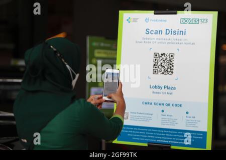 Bogor, Indonesia. 24th Aug, 2021. A woman scans the QR code to enter a shopping mall after the Indonesian government has allowed malls or shopping centers to reopen after the level public activity restrictions have been reduced from 4 to 3, in Bogor, West Java, Indonesia on August 24, 2021. (Photo by Adriana Adie/INA Photo Agency/Sipa USA) Credit: Sipa USA/Alamy Live News Stock Photo